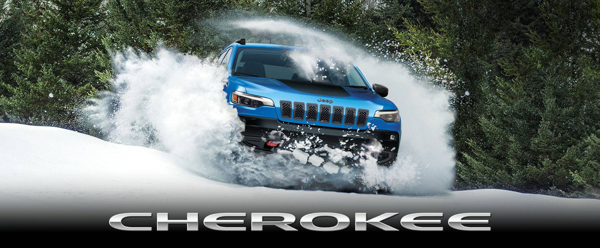 A blue 2023 Jeep Cherokee Trailhawk kicking up white powder as it plows through deep snow. Cherokee.